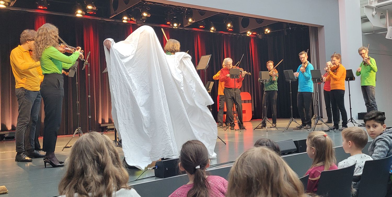 Foto vom WKO-Orchester auf der Bühne Moderator Juri Tetzlaff als Gespenst verkleidet